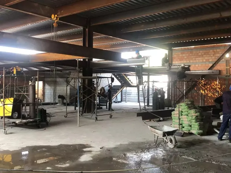 Equipe montando vigas metálicas sob a laje do Só Marcas Outlet